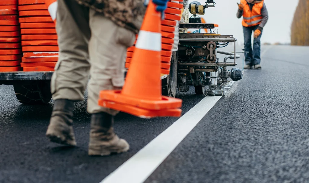 Close-up view of freshly painted yellow and white striping on an asphalt surface, indicating clearly marked parking spaces and traffic lanes for increased safety and organization.