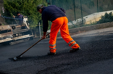 An asphalt surface being evenly coated with a dark black sealant, protecting the pavement from UV rays, oxidation, and water damage while restoring its original color and appearance.
