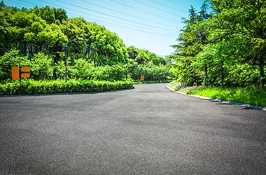 A residential asphalt paving project showcasing workers resurfacing a driveway, with fresh asphalt being laid, leveled, and compacted to create a smooth, black surface that enhances the home's curb appeal.